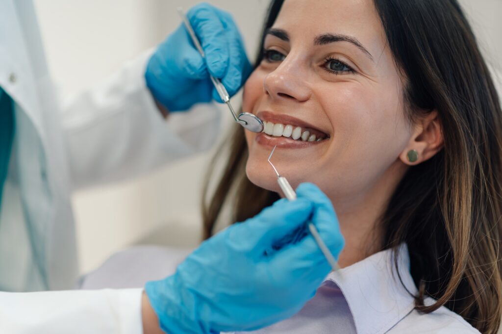Dentist examining teeth of smiling woman during dental checkup