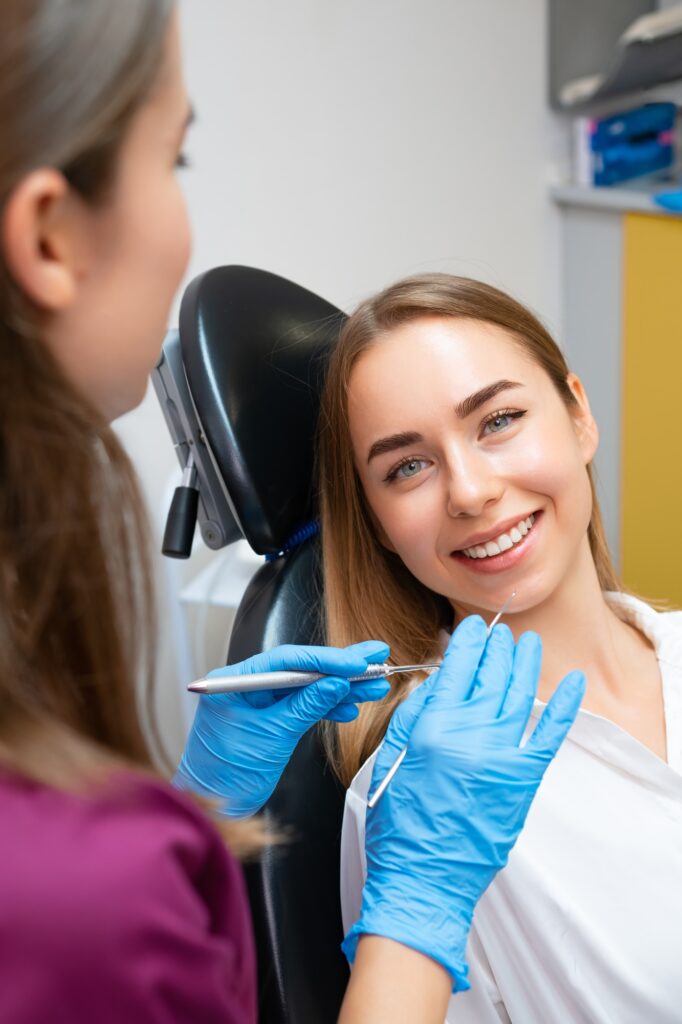Dentist treating teeth of female patient with perfect smile