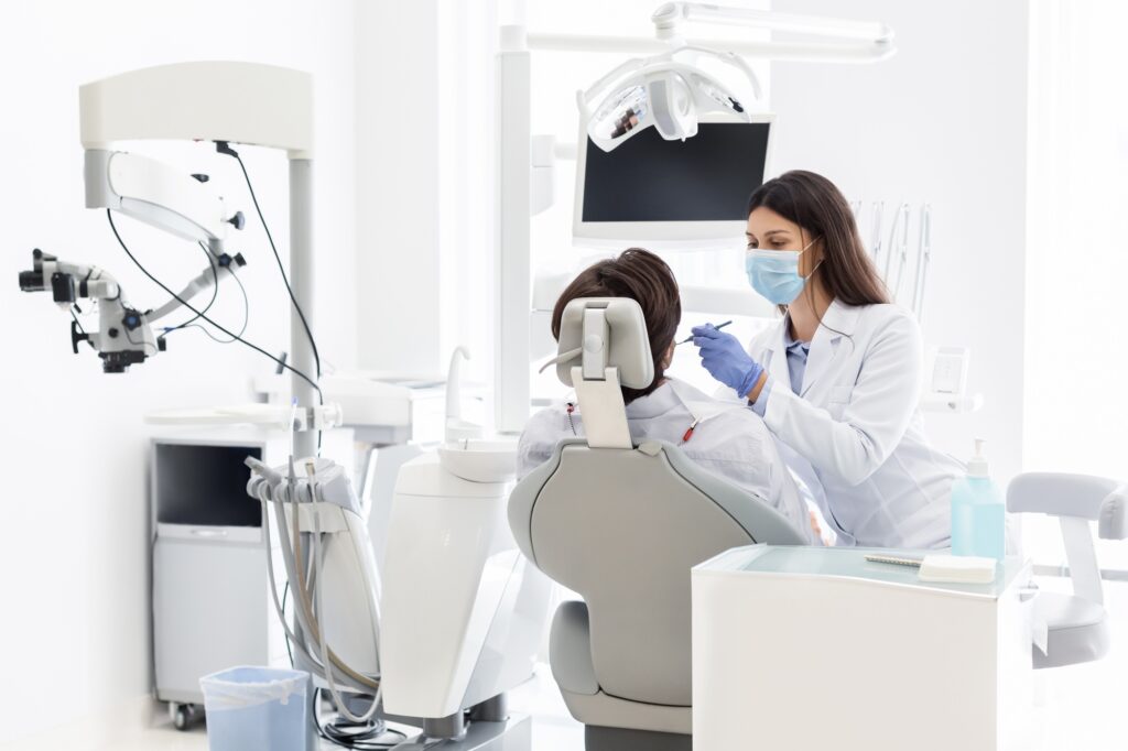 Pretty dentist doctor treating patient in dental clinic