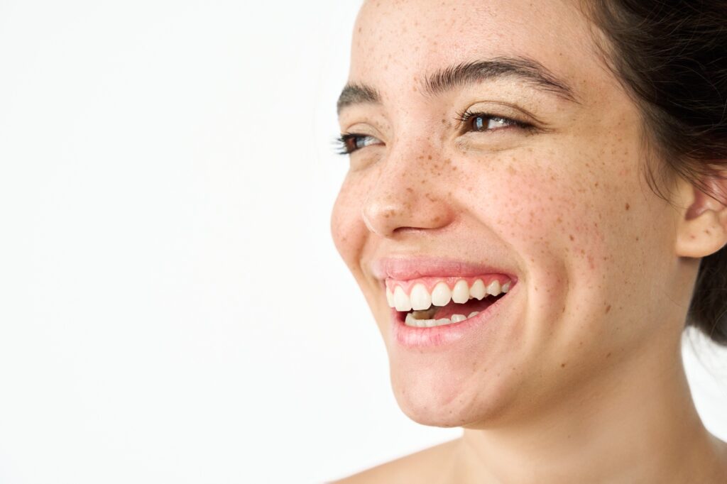 Happy young woman freckled face dental smile isolated on white. Skin care.